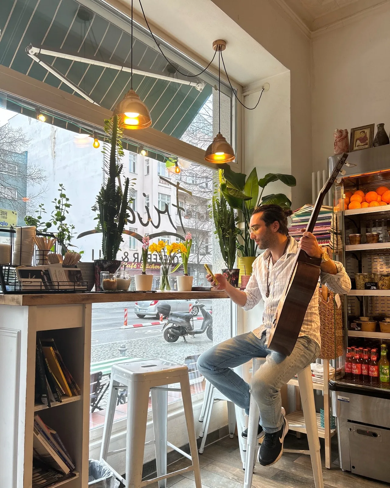 Sami spielt Bass auf der Fensterbank im Café